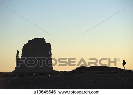 Stock Photograph - Silhouette of woman by butte in Monument Valley, Arizona, USA. Fotosearch