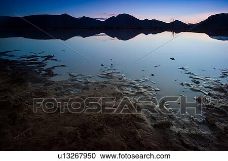 Stock Image - Silhouetted mountain ranges on horizon over water, Cape Town, Western Cape, South Africa. Fotosearch