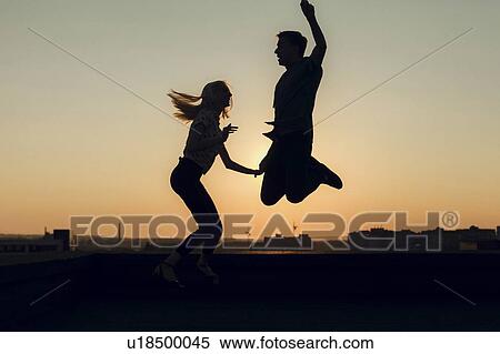 Silhouettes of young couple jumping at sunset View Large Photo Image Stock Photography - Silhouettes of young couple jumping at sunset. Fotosearch