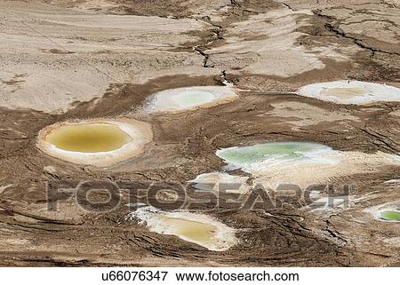 Stock Photo - Sinkhole caused by the receding water level of the Dead Sea, Israel. A hot water spring fills the hole.. Fotosearch