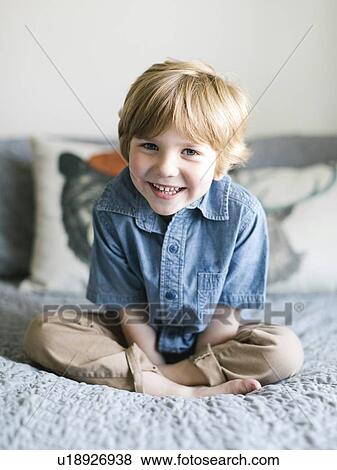 Smiling boy sitting on bed View Large Photo Image Stock Photo - Smiling boy sitting on bed. Fotosearch
