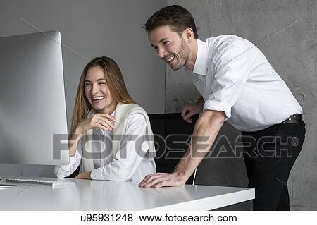 Stock Photo - Smiling businesspeople using computer. Fotosearch