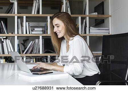 Smiling businesswoman working on laptop View Large Photo Image Stock Image - Smiling businesswoman working on laptop. Fotosearch