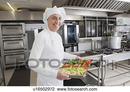 Smiling chef holding tray of vegetables View Large Photo Image Stock Image - Smiling chef holding tray of vegetables. Fotosearch