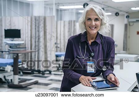 Smiling doctor holding digital tablet in hospital View Large Photo Image Stock Image - Smiling doctor holding digital tablet in hospital. Fotosearch