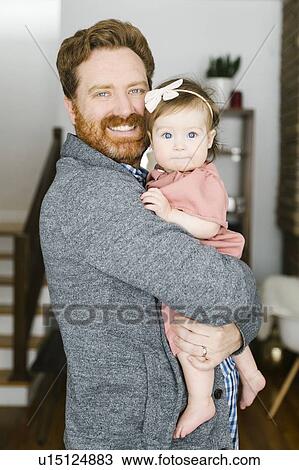 Stock Image - Smiling father holding his baby girl. Fotosearch