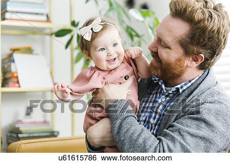 Smiling father holding his baby girl View Large Photo Image Stock Photograph - Smiling father holding his baby girl. Fotosearch