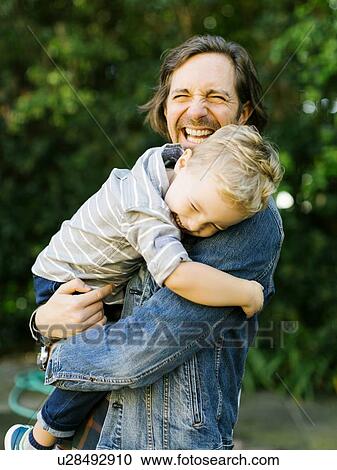 Stock Image - Smiling father holding his son. Fotosearch