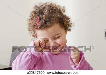 Smiling girl rubbing her eye View Large Photo Image Stock Photo - Smiling girl rubbing her eye. Fotosearch