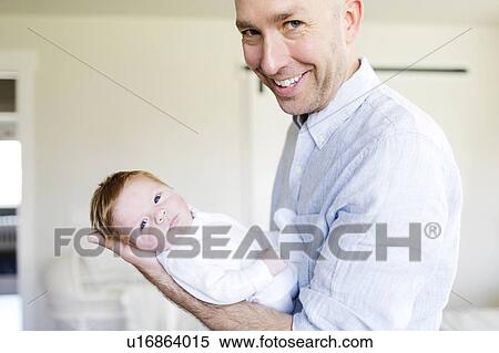 Stock Photography - Smiling man holding his baby son. Fotosearch