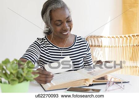 Smiling mature woman looking at scrapbook View Large Photo Image Stock Image - Smiling mature woman looking at scrapbook. Fotosearch