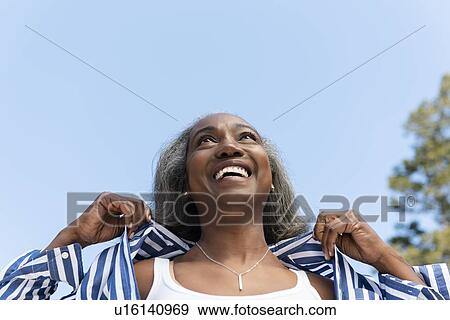 Smiling mature woman under clear sky View Large Photo Image Stock Photo - Smiling mature woman under clear sky. Fotosearch