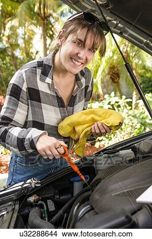 Smiling woman checking car engine oil View Large Photo Image Picture - Smiling woman checking car engine oil. Fotosearch