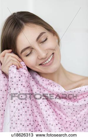 Smiling woman feeling soft fabric on her cheek View Large Photo Image Stock Image - Smiling woman feeling soft fabric on her cheek. Fotosearch