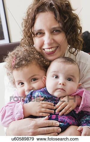 Smiling woman holding her two daughters View Large Photo Image Stock Photo - Smiling woman holding her two daughters. Fotosearch