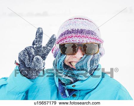 Smiling woman making peace gesture in snow View Large Photo Image Stock Photo - Smiling woman making peace gesture in snow. Fotosearch