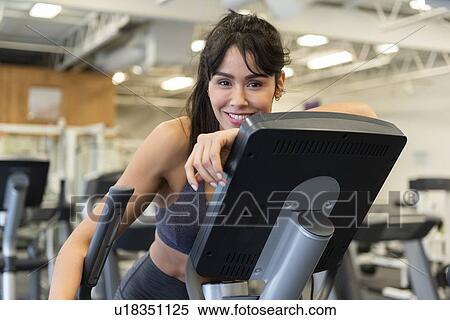 Stock Photography - Smiling woman on elliptical machine. Fotosearch