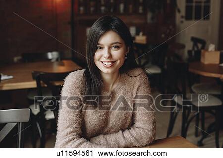 Stock Image - Smiling woman sitting in restaurant. Fotosearch