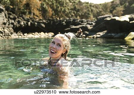 Stock Image - Smiling woman swimming in sea. Fotosearch