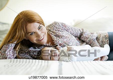 Smiling woman with her newborn son lying on a bed View Large Photo Image Stock Photography - Smiling woman with her newborn son lying on a bed. Fotosearch