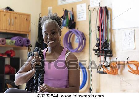 Picture - Smiling woman with rope in gym. Fotosearch