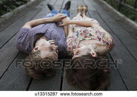 Stock Photo - Smiling young couple lying on boardwalk. Fotosearch