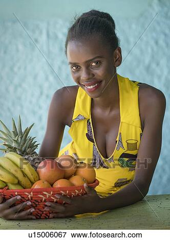 Stock Photo - Smiling young woman holding fruit bowl. Fotosearch