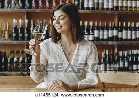 Picture - Smiling young woman holding glass of white woman. Fotosearch