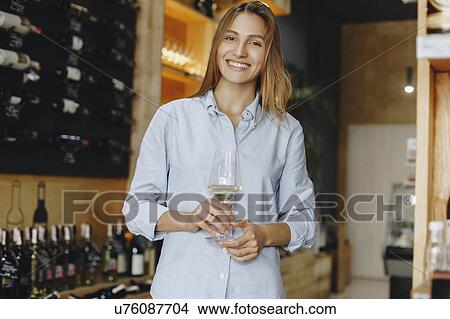 Smiling young woman holding glass of white wine View Large Photo Image Picture - Smiling young woman holding glass of white wine. Fotosearch