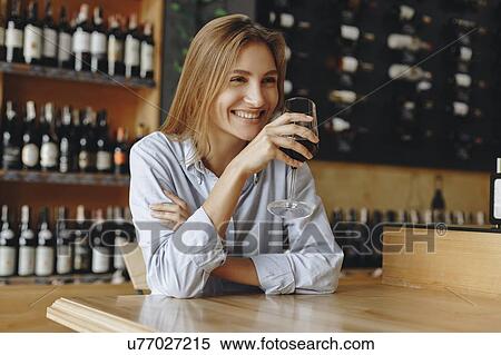 Stock Photography - Smiling young woman holding glass of red wine. Fotosearch