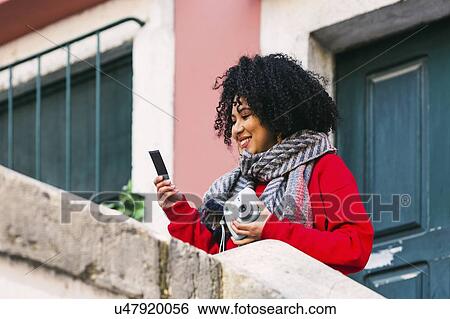Smiling young woman holding Polaroid camera and photograph View Large Photo Image Stock Photograph - Smiling young woman holding Polaroid camera and photograph. Fotosearch