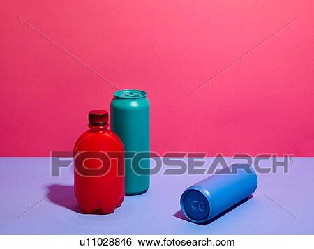 Stock Photograph - Still life of turquoise and blue drink cans with red bottle and pink background. Fotosearch