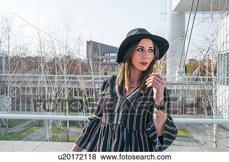 Stock Photo - Stylish young woman in felt hat outside office building, Turin, Piemonte, Italy. Fotosearch