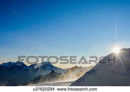 Picture - Sun peeking behind mountain, Saas-Fee, Valais, Switzerland. Fotosearch