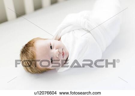 Picture - Swaddled baby boy in cot. Fotosearch
