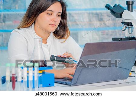 Stock Image - Technician in quality control laboratory using a refractometer.. Fotosearch