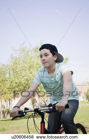 Teenage boy cycling in park View Large Photo Image Stock Photo - Teenage boy cycling in park. Fotosearch