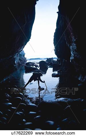 Stock Photo - Teenage boy exploring care with rocks in La Jolla, California. Fotosearch