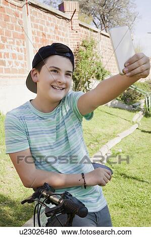 Teenage boy taking selfie while leaning on bicycle View Large Photo Image Stock Image - Teenage boy taking selfie while leaning on bicycle. Fotosearch
