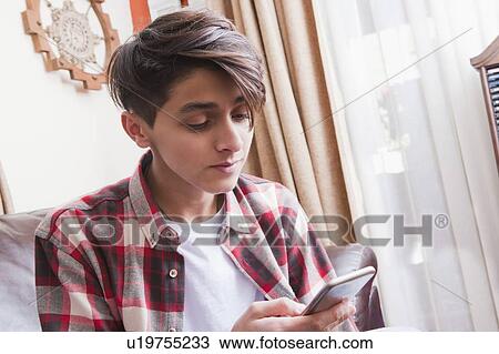 Stock Image - Teenage boy using smart phone. Fotosearch