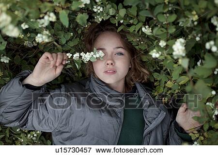 Stock Photo - Teenage girl in bush with flowers. Fotosearch
