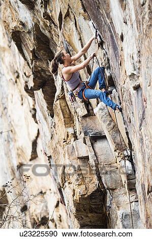 Stock Image - Teenage girl rock climbing. Fotosearch