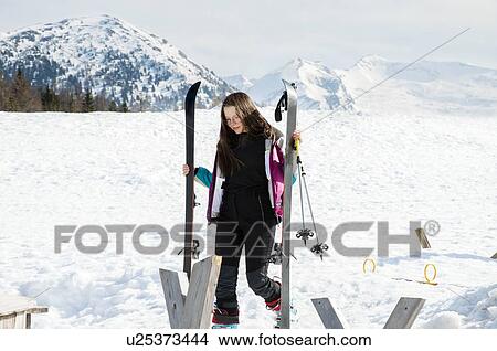 Picture - Teenage girl skier carrying skis in snow covered landscape, Tyrol, Styria, Austria. Fotosearch
