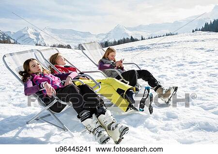 Three teenage girl skiers sitting in deck chairs in snow covered landscape, Tyrol, Styria, Austria View Large Photo Image Stock Image - Three teenage girl skiers sitting in deck chairs in snow covered landscape, Tyrol, Styria, Austria. Fotosearch