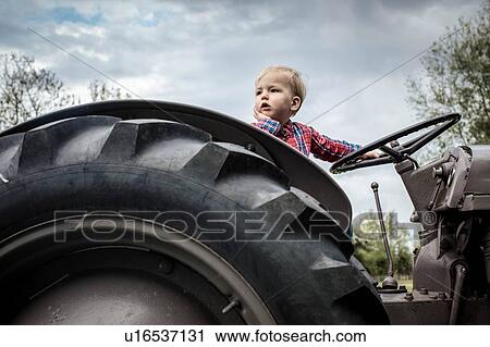Stock Image - Toddler in deep thought on tractor. Fotosearch