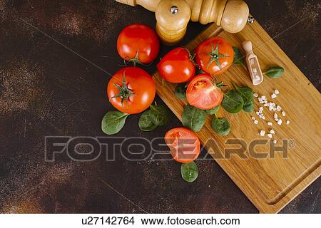 Tomatoes, basil and salt on wooden cutting board View Large Photo Image Picture - Tomatoes, basil and salt on wooden cutting board. Fotosearch