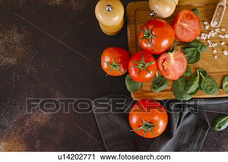 Stock Image - Tomatoes, basil and salt on wooden cutting board. Fotosearch