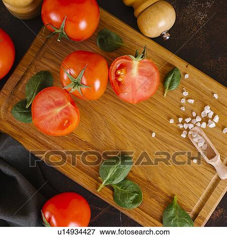 Stock Photo - Tomatoes, basil and salt on wooden cutting board. Fotosearch
