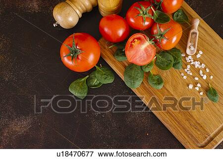 Stock Photo - Tomatoes, basil and salt on wooden cutting board. Fotosearch