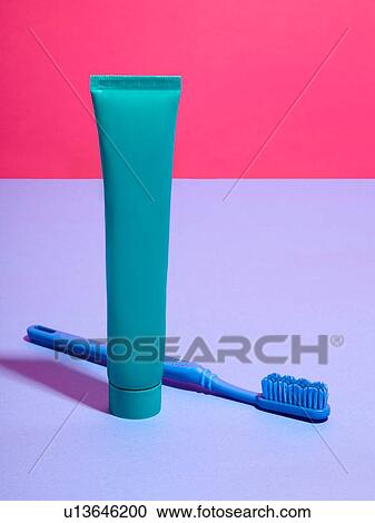 Stock Image - Toothbrush and toothpaste against pink and lilac background. Fotosearch